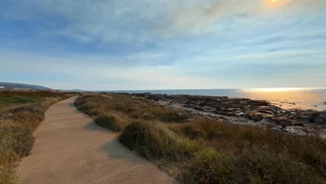 long and curved stone road leading into horizon near north atlantic ocean in portugal during sunset