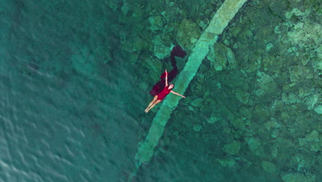 top down view of woman in red dress swimming in adriatic sea in croatia - drone shot