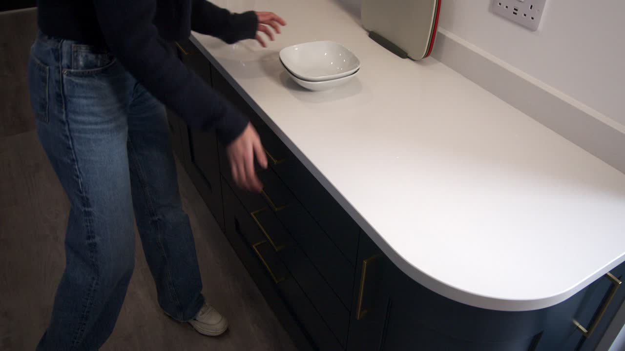 modelo femenino abriendo cajones de cocina y colocando, poniendo en dos tazones y caminando en una cocina moderna