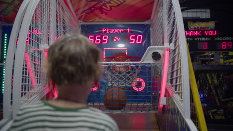 a young woman is playing an arcade basketball game.