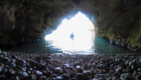 uomo che sale nell'acqua all'interno della grotta nell'isola di cefalonia, in grecia