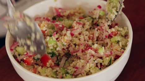 close up of a bowl of couscous salad being mixed in a bowl