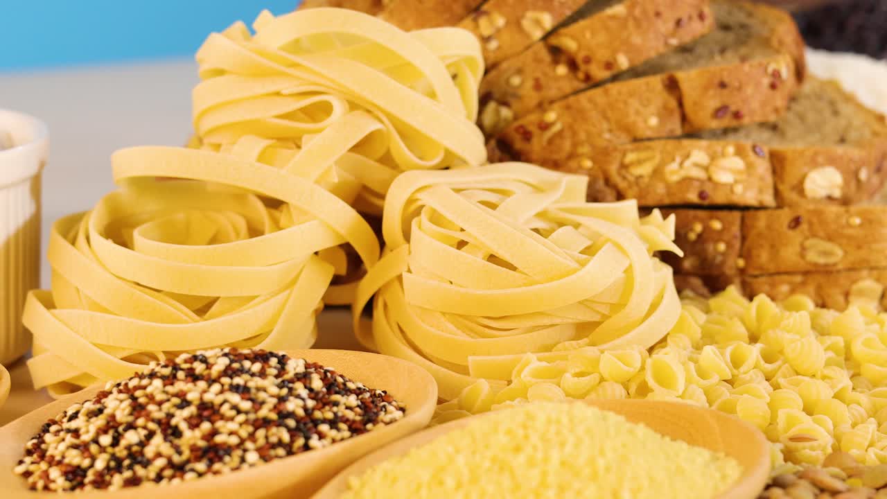 A vibrant arrangement of various grains, pasta, and bread under bright lighting, showcasing diverse textures and colors