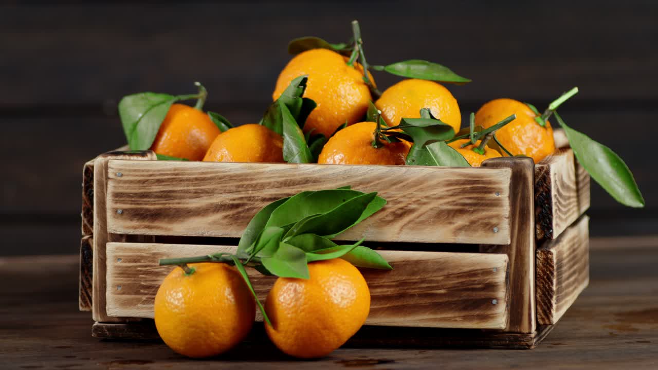 Tangerines in a wooden box slowly rotate.
