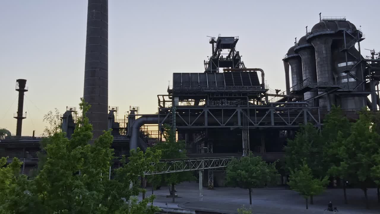 puesta de sol y cielo amarillo sobre las instalaciones de la fábrica en desuso en landschaftspark duisburg en alemania