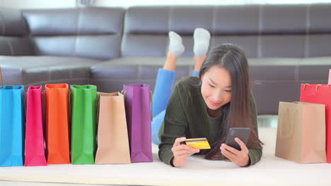 pretty woman addicted to shopping buying stuff online with smartphone and credit card in privacy of home, full frame