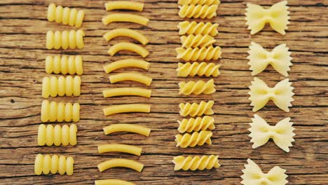 Various-pasta-aligned-vertically-on-wooden-table-background-