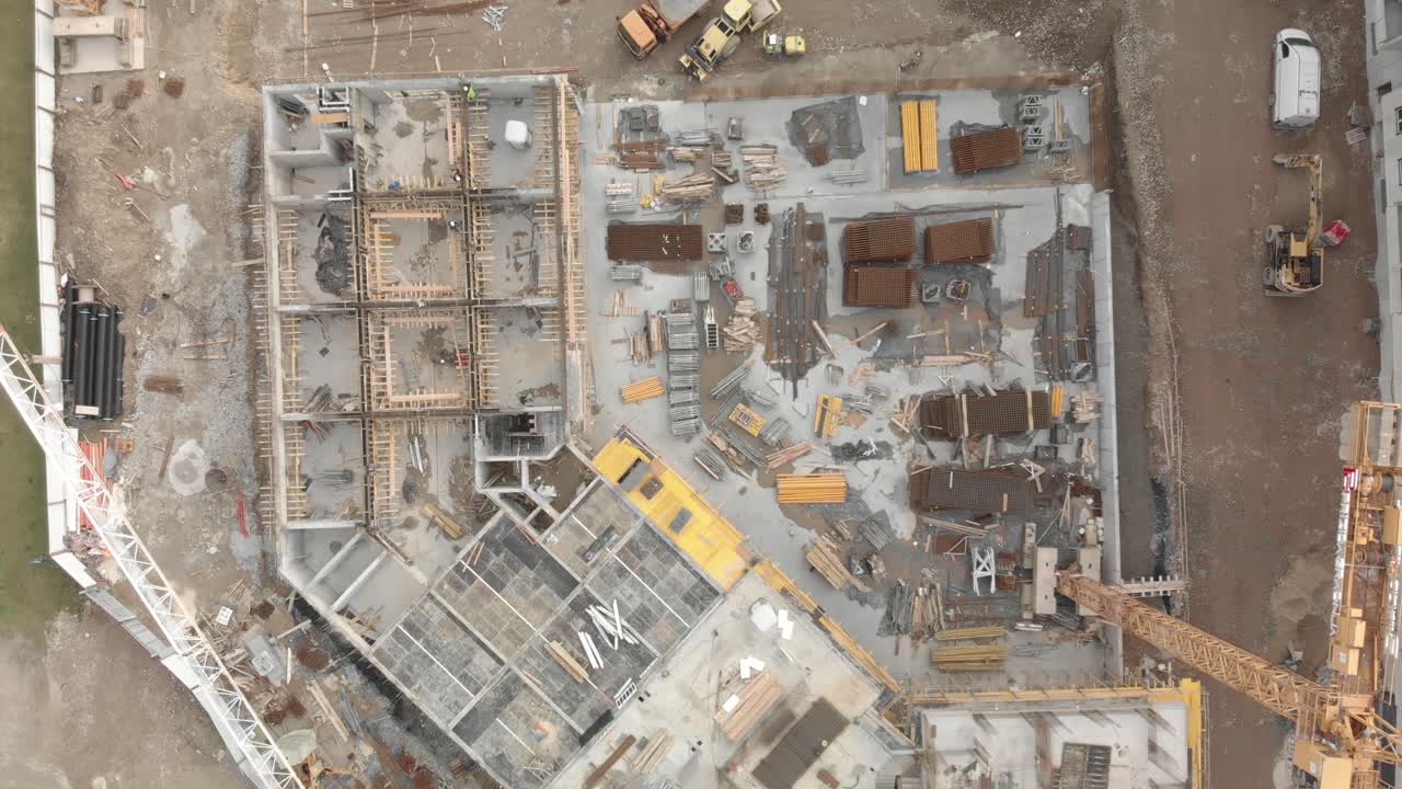 Aerial top eye's bird view of a construction site with workers and big crane excavator. New urban residential quarter