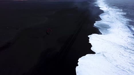 aerial view of bright red quad bikes on iceland black sand beach, next to the ocean