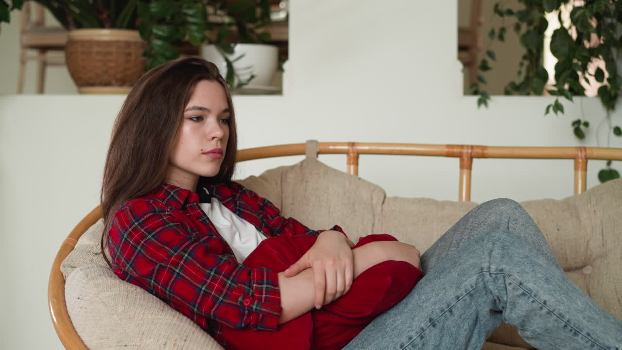 женщина с депрессивным расстройством дома. печальная женщина проходит через тяжелый разрыв с любимым человеком, сидящим на кресле папасана. состояние психического здоровья