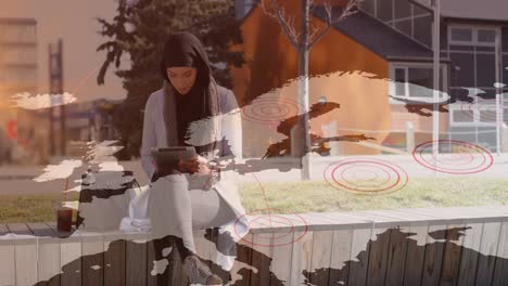 animation of asian woman in hijab using tablet in street over world map