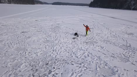 zoom out footage of young man walking from one hole to another with his bait and tackle hoping to be more successful in the new hole.
