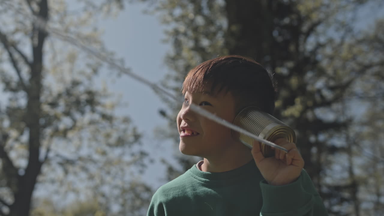 Boy playing with a tin can phone outdoors