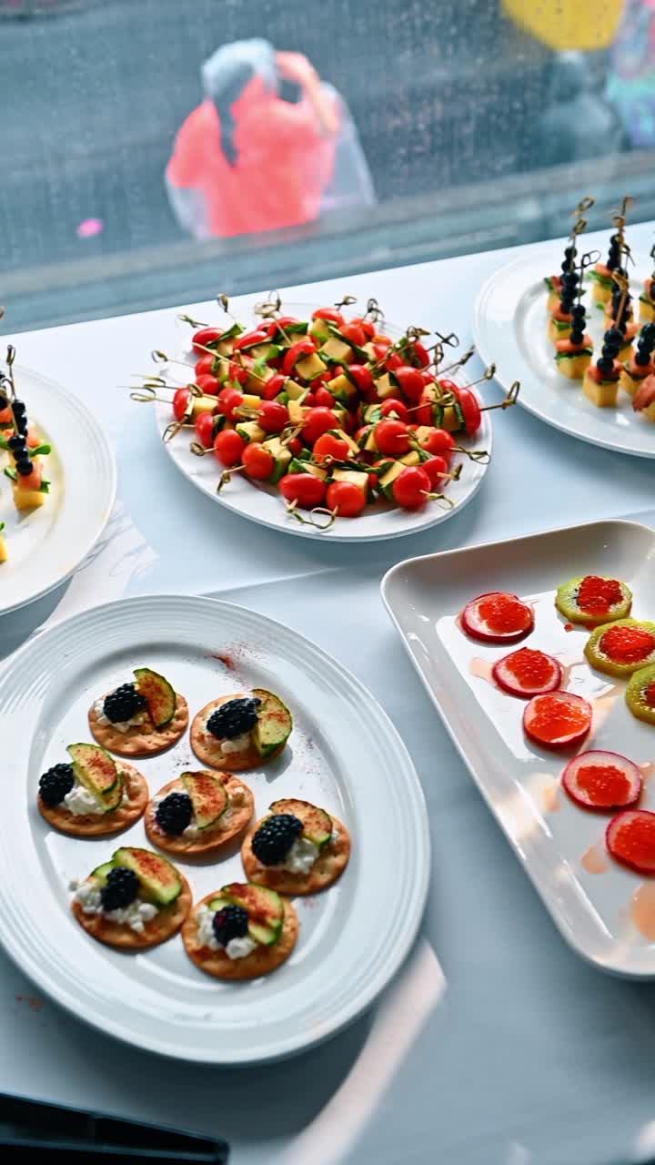 Selezione di antipasti gourmet su piatti bianchi a un evento di catering. Canapè assortiti con spiedini caprese, salmone, more e ravanelli con caviale su una tovaglia bianca.