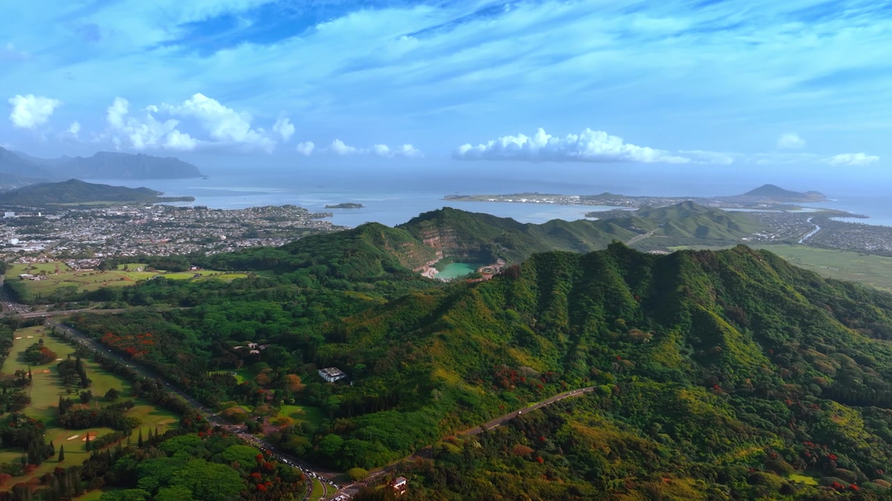 Fantastico scenario di montagne verdi delineate dall'autostrada trafficata. Area popolosa sullo sfondo. Honolulu, Hawaii, USA. Veduta aerea