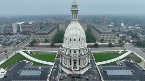 american flag waving on michigan state capitol building in lansing, mi