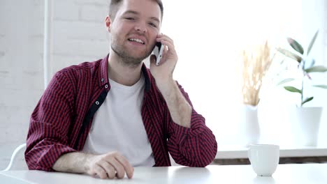 un joven hablando por teléfono en la oficina.