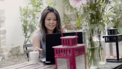 pretty woman sitting at table in outdoor cafe with laptop