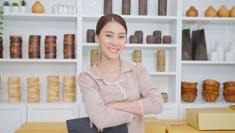 portrait of asian beautiful woman selling vase product online at home. young attractive girl stand with confidence checking goods in warehouse store for customer then cross arm and looking at camera.