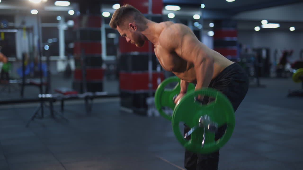 Muscular handsome man pulling up big weight. Bodybuilder working hard at gym.