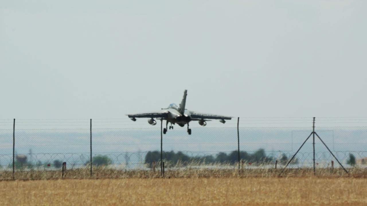 Aereo militare che atterra su una pista sopra un campo