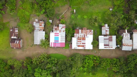 Vista-Aérea-Alejándose-De-Tiro,-Vistas-Panorámicas-Cabañas-De-Troncos-En-La-Selva-Amazónica-En-Un-Día-Nublado-En-Colombia