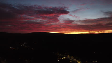 slow golden sunset filmed high above the evening streets of todmorden in the hills of west yorkshire , intense reds and orange colours firing over the dark horizon