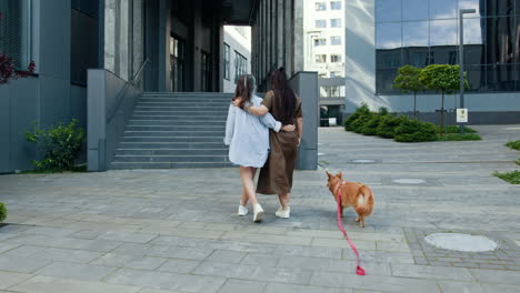 two women walking their dog in a city
