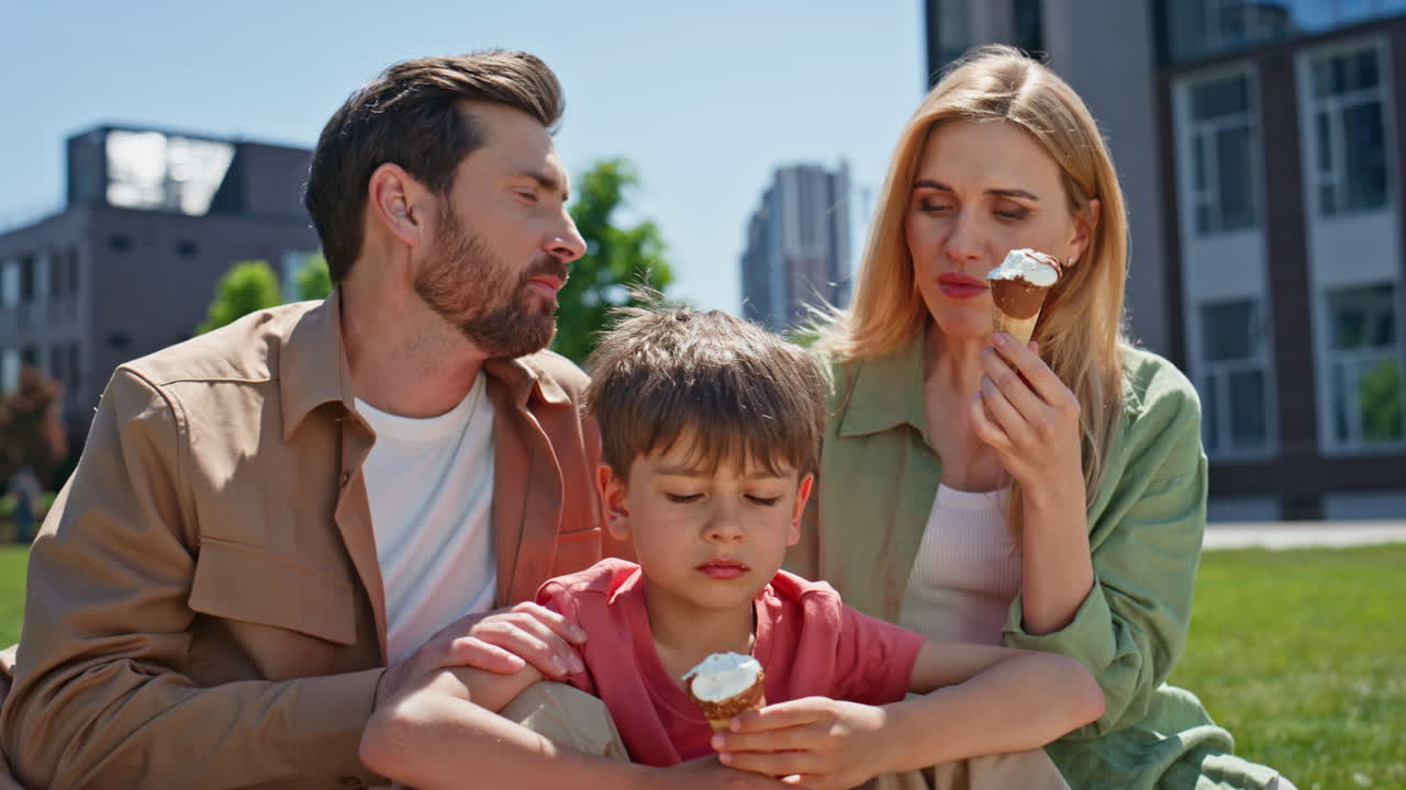 Parents child enjoying ice-cream weekend picnic together closeup. Happy family