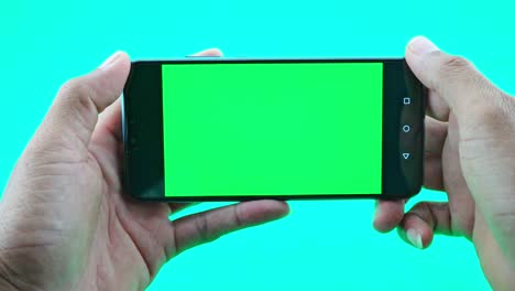 close up of man hand holding the smartphone or cell phone on green screen background