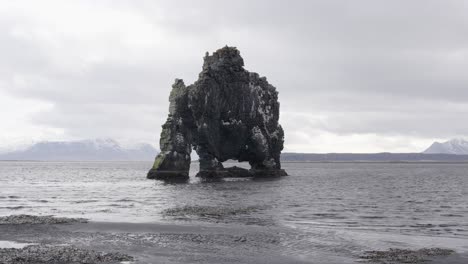 Vista-Desde-La-Playa-De-Arena-Negra-Sobre-La-Formación-Rocosa-De-Hvitserkur-Durante-El-Día-Nublado