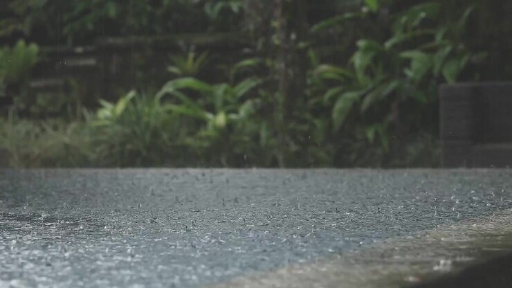 Lluvia tropical sobre una piscina infinita en la selva balinesa, gotas de lluvia en cámara lenta