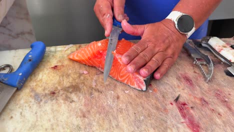 person filleting a large piece of fresh salmon fish