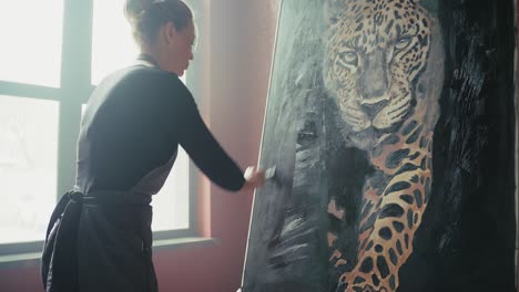 woman artist painting a leopard portrait in a studio