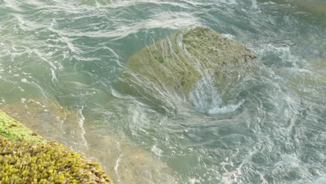 close-up en cámara lenta de las olas golpeando y pasando una gran roca costera en el mar británico en seaford