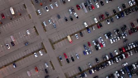 Drone rotates downward above organized city parking lot filled with parked vehicles