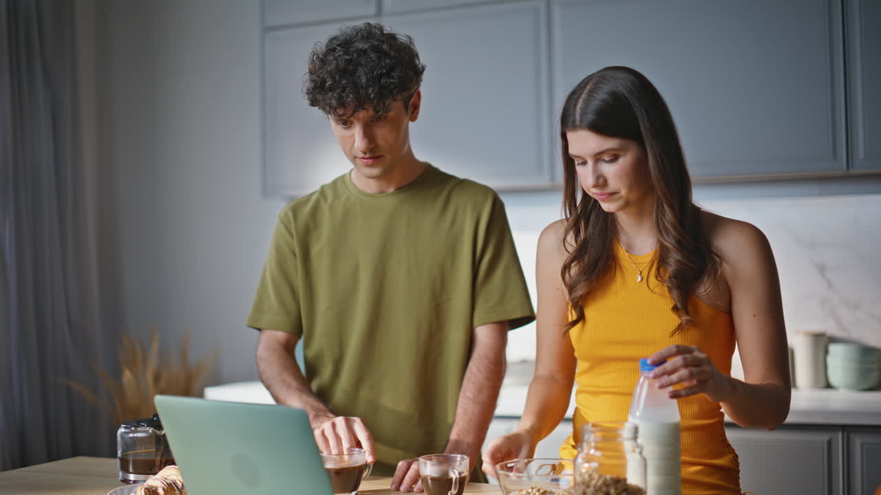 Cooking pair looking laptop screen in kitchen closeup. Couple watching computer