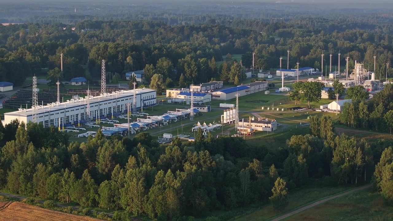 Smooth cinematic drone footage of the Incukalns Underground Gas Storage infrastructure during sunrise in Latvia. Detailed aerial view of natural gas processing facilities, pipelines, industrial buildi