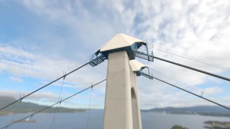 White-pillar-of-Bomla-suspension-bridge-with-cloudy-sky,-FPV-diving-down-view