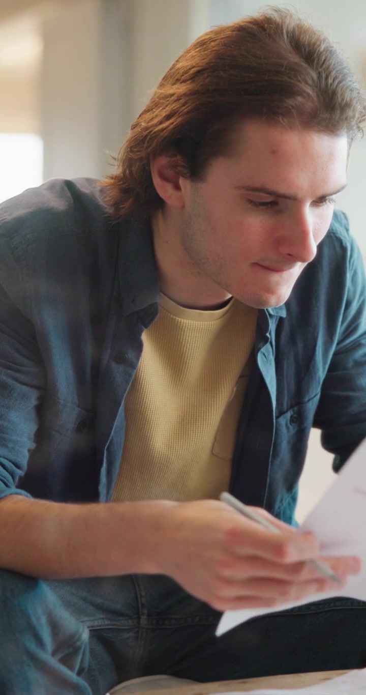 Giovane uomo che esamina documenti e riflette in uno spazio di lavoro luminoso