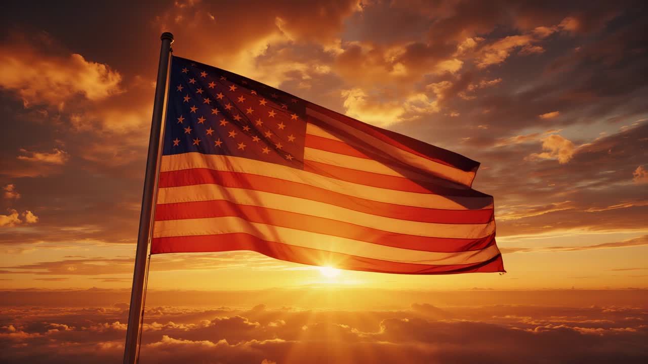 Billowing American flag on flagpole in rising breeze above clouds at sunrise, with golden glow