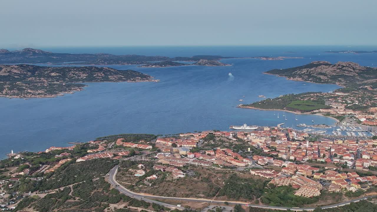 Vista della costa sarda con barche e acqua blu durante una giornata di sole