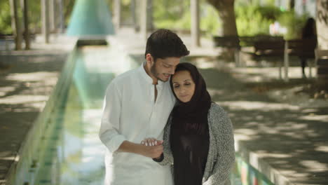 Feliz-Pareja-Musulmana-Abrazándose-Y-Tomándose-De-La-Mano-En-El-Parque.