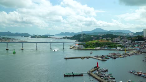 Barco-De-Pesca-Cruzando-Bajo-El-Puente-Geoje-Durante-El-Día-En-La-Isla-Geojedo-En-Gyeongsangnam-do,-Corea-Del-Sur