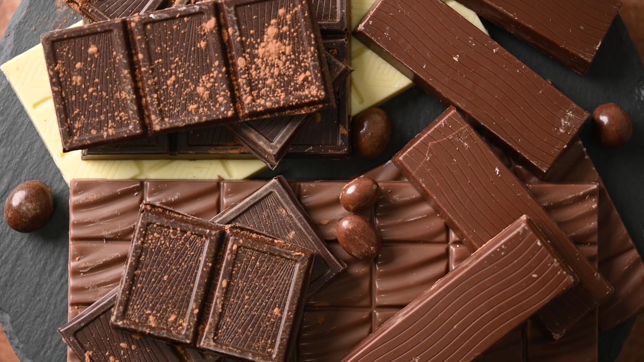 Blandede mørke, mælke- og hvide chokoladebarer på en skiferplade