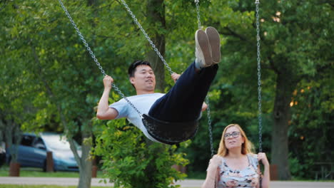 Young-Couple-Having-Fun-Swinging-On-A-Swing-A-Good-Time-Together-An-Active-Young-Family-Expecting-A