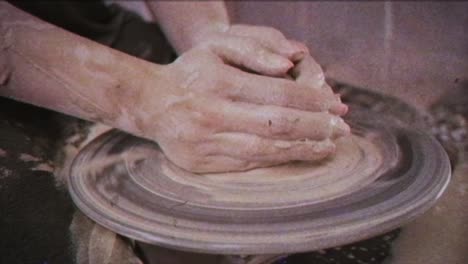 a potter teaches a woman to make clay dishes. a man takes a woman's hands. vintage effect.