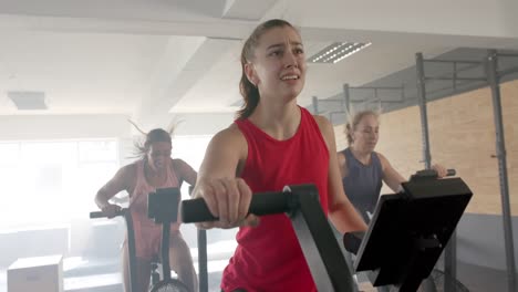 Cansadas-E-Inalteradas-Mujeres-Diversas-Entrenando-En-Bicicletas-Elípticas-En-Clases-De-Fitness-Grupales,-Cámara-Lenta