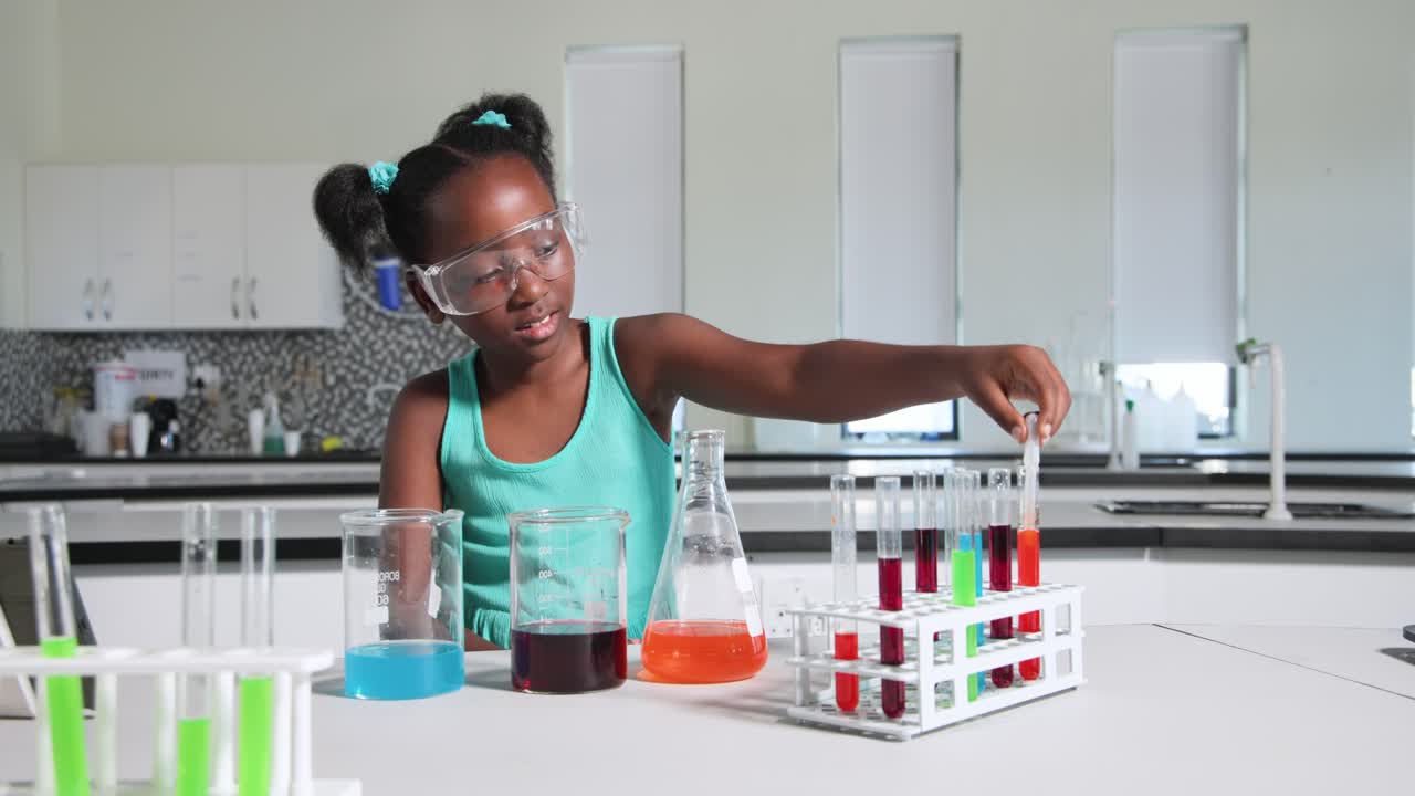African teen girl following tablet goggles-on drawing orange flask with pipette into rack at school