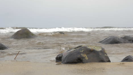 Zeitlupenansicht-Des-Wassers,-Das-Sich-Zwischen-Steinen-Am-Sandstrand-Der-Insel-Gran-Canaria-In-Spanien-Bewegt